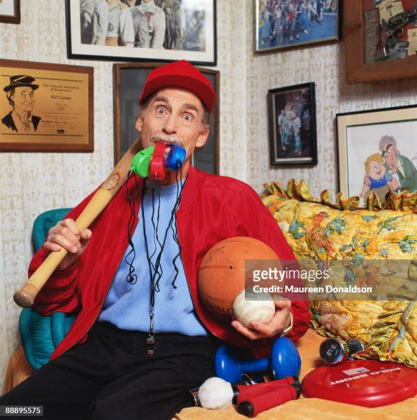 Twenty years on, American comic actor Sid Caesar recreates his role as Coach Calhoun in the 1978 musical film 'Grease'. On the wall behind him is a...