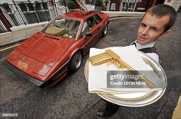 Man stands next to the 1980 Lotus Turbo Esprit from the James Bond film "For Your Eyes Only" with a limited edition replica pistol from "The Man with...