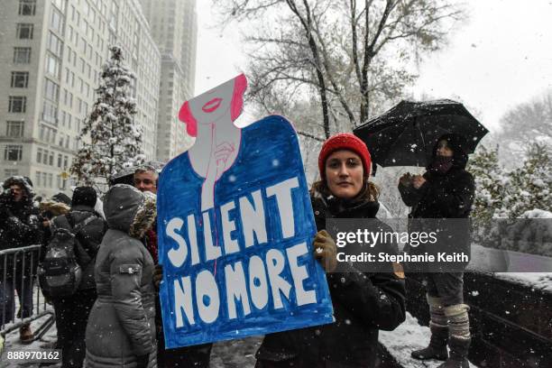 People carry signs addressing the issue of sexual harassment at a #MeToo rally outside of Trump International Hotel on December 9, 2017 in New York...