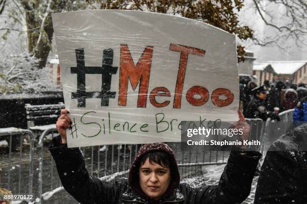 People carry signs addressing the issue of sexual harassment at a #MeToo rally outside of Trump International Hotel on December 9, 2017 in New York...