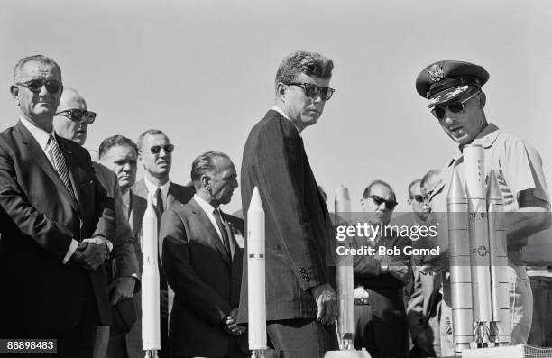 American President John F. Kennedy is briefed by Director of Eastern Test Range Lt. Col. Dan F. Thompson on a display of scale models of booster...