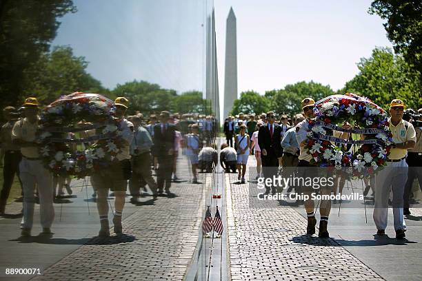Volunteers carry a wreath along Vietnam Veterans Memorial, or The Wall, during a ceremony commemorating the 50th anniversary of the first American...
