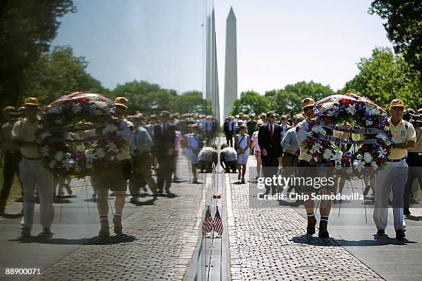 Volunteers carry a wreath along Vietnam Veterans Memorial, or The Wall, during a ceremony commemorating the 50th anniversary of the first American...