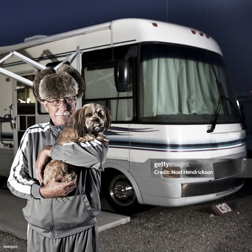 Older man holding dog in front of RV