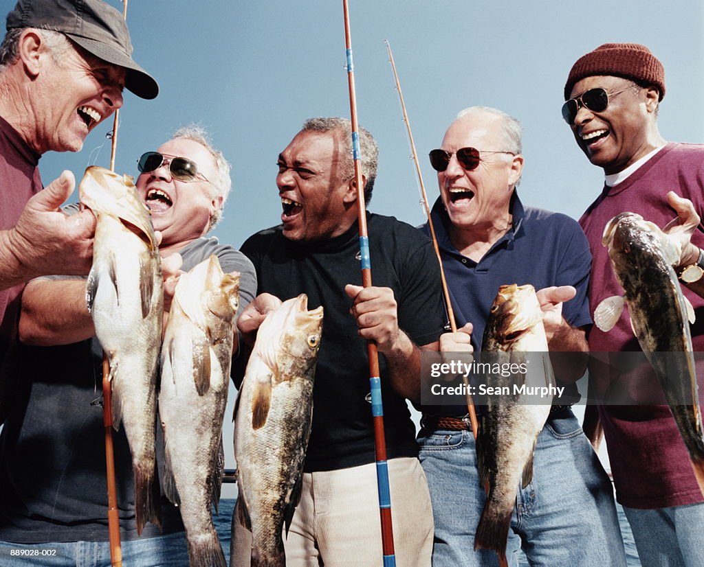 Five mature men holding catch (calico bass) on deck of boat