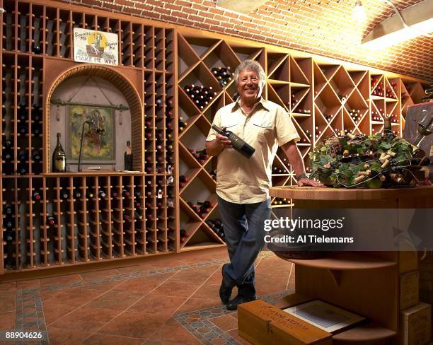 Where Are They Now: Portrait of former driver Mario Andretti holding a bottle of his Andretti Winery wine in cellar at his home Villa Montona....