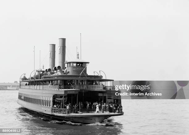 View of the Staten Island ferry 'Manhattan' as it approaches the pier, New York, New York, early 1900s. Signs on either side read 'Women' and 'Men.'