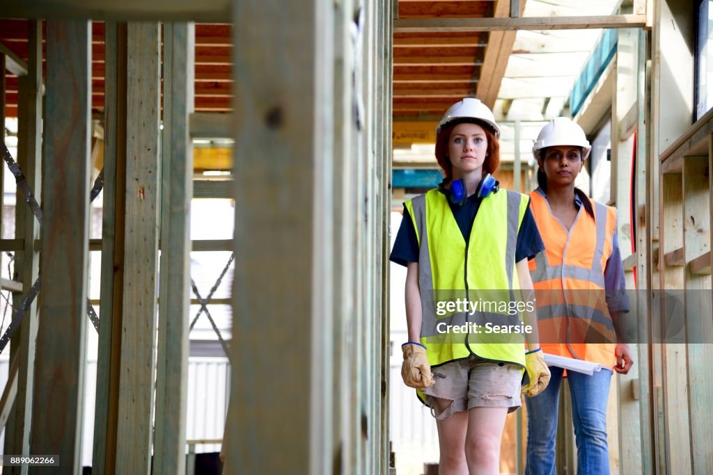 SYD112017 Female Architect and construction worker walking through the house frame