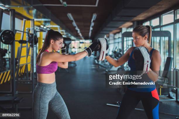 female boxer sparring with her female trainer - kickboxing equipment stock pictures, royalty-free photos & images