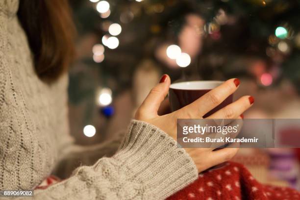 drinking coffee next to christmas tree - heißes getränk stock-fotos und bilder