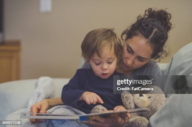 mamá e hijo lectura libro juntos en sala de estar - weakness fotografías e imágenes de stock