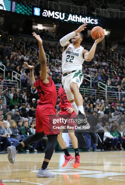 Miles Bridges of the Michigan State Spartans shoots over Christian Musoko of the Southern Utah Thunderbirds at Breslin Center on December 9, 2017 in...