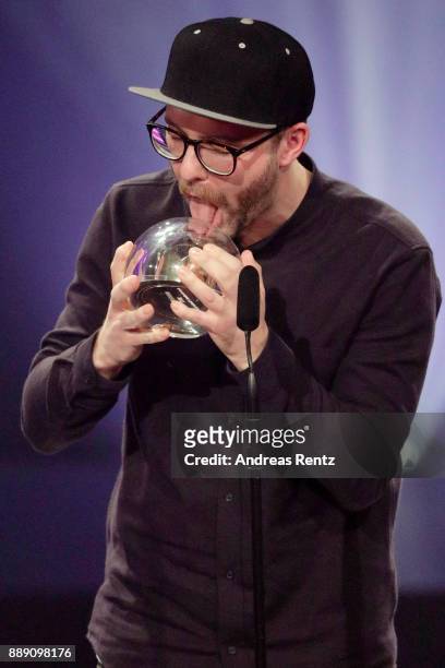 Mark Forster licks his award for best artist on stage during the 1Live Krone radio award at Jahrhunderthalle on December 07, 2017 in Bochum, Germany.