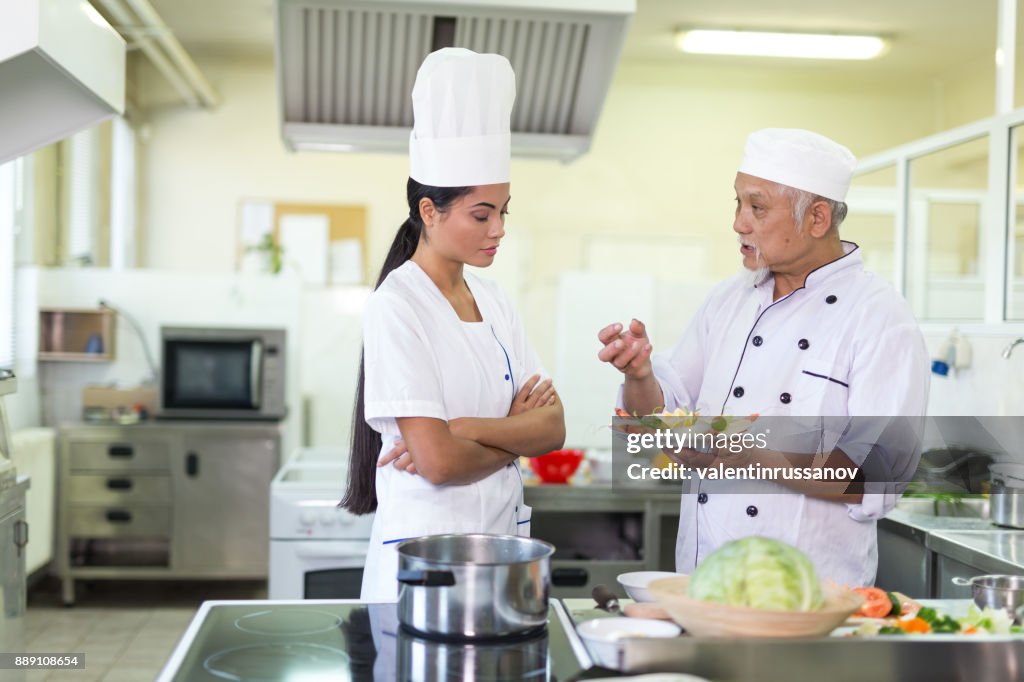Chef and assistant preparing asian food in restaurant's kitchen