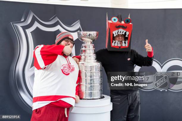 Darren McCarty and a fan pose for a photo with the Stanley Cup during the NHL Centennial Fan Arena on December 3, 2017 in Detroit, Michigan.