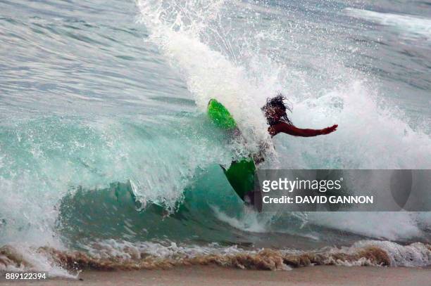 Surfer rides a wave on his wake board in Puerto Escondido, Oaxaca state, Mexico on December 9, 2017. / AFP PHOTO / David GANNON