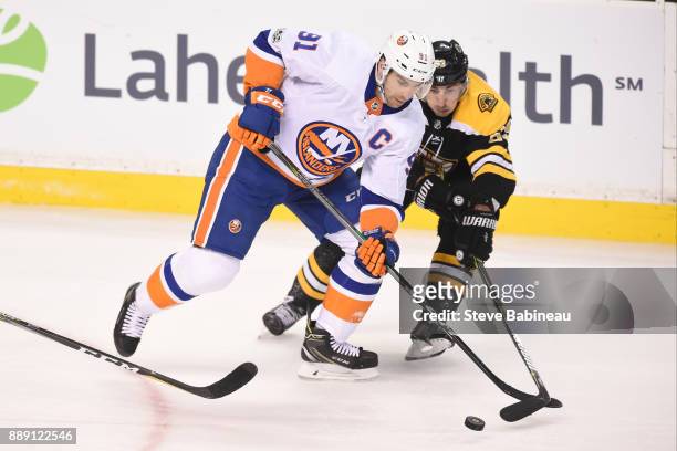 John Tavares of the New York Islanders fights for the puck against Brad Marchand of the Boston Bruins at the TD Garden on December 9, 2017 in Boston,...