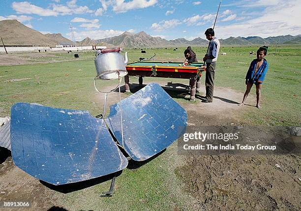 Villagers playing pingpong in a Central Tibet village near Lhatse. Food gets cooked in a Solar cooker. Ping-pong is a Chinese game somewhat similar...