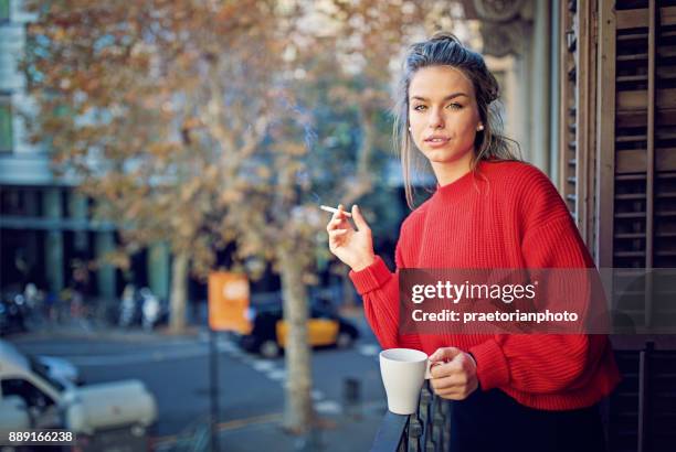 jong meisje is roken sigaretten en drinken koffie op het balkon in de ochtend - beautiful women smoking cigarettes stockfoto's en -beelden