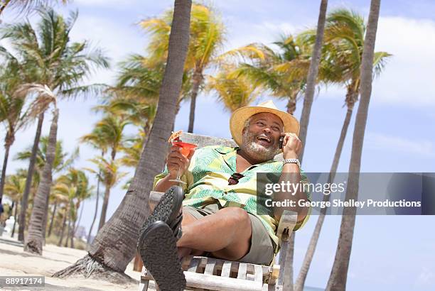 relaxed man on vacation talking on cell phone - man on the beach relaxing in deckchair fotografías e imágenes de stock