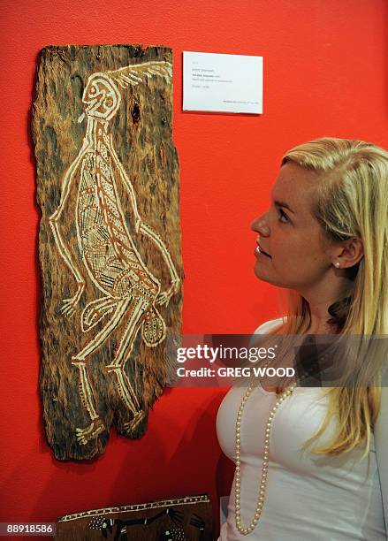 Sotheby's employee Grace Livingston-Clarke admires 'The Man, Noulabil', a 1948 natural earth pigment painting on eucalyptus bark by an unknown...