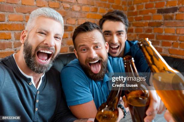 three friends enjoying at pub and taking selfie - beer bottle mouth stock pictures, royalty-free photos & images