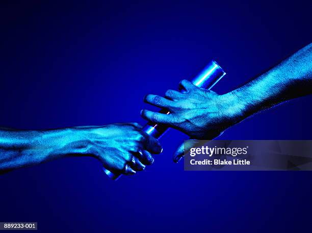 hands passing baton (blue tone) - pasar fotografías e imágenes de stock