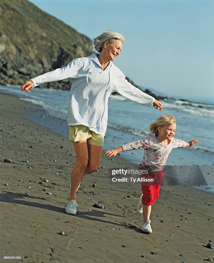 Grandmother and granddaughter (4-6) playing on seashore