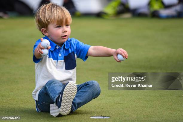 Tatum Johnson, son of Paulina Gretzky and Dustin Johnson, plays with golf balls on the 18th hole green after his dad's 1-up victory during the...