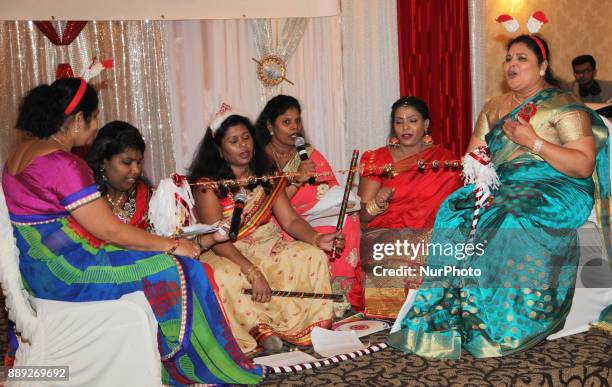 Tamil women singing Christmas songs while hitting a string with jingle bells during the V Rambaikulam Girls Maha Vidyalayam Old Students Association...