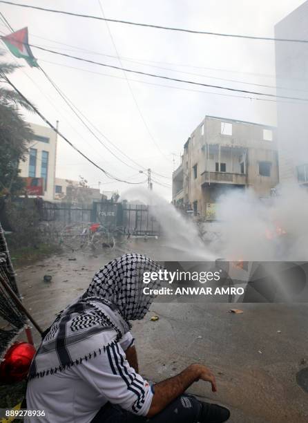 Lebanese security forces use a water hose to extinguish a fire in a dumpster during a demonstration outside the US embassy in Awkar, on the outskirts...