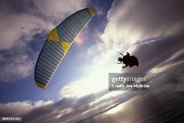 paraglider in mid-air over ocean - paragliding stock pictures, royalty-free photos & images