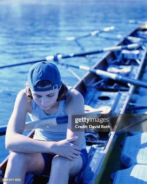 young woman sitting in boat, with pensive expression - single scull stockfoto's en -beelden