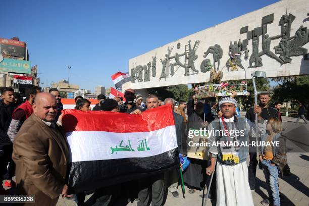 Iraqis wave the national flag at the Tahrir Square in the capital Baghdad on December 10 during a military parade to mark the end of a three-year war...