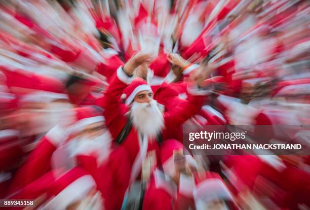 Picture taken with zoom effect shows charity runners dressed as Father Christmas participating in the 'Santa Run' charity fun run in Stockholm on...