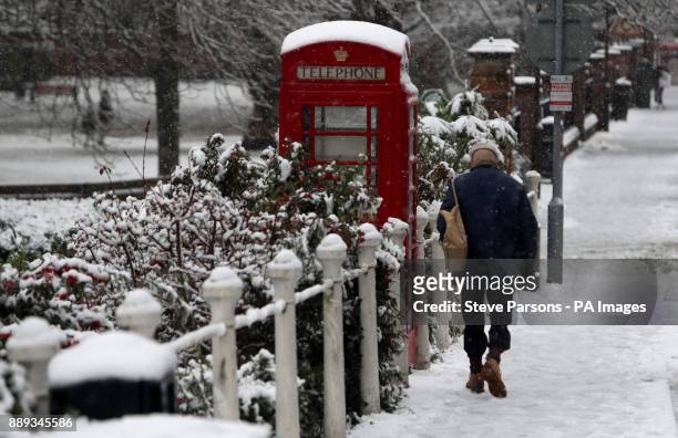 Man walks past a snow covered phone box in Marlow, Buckinghamshire, as heavy snowfall across parts of the UK is causing widespread disruption,...