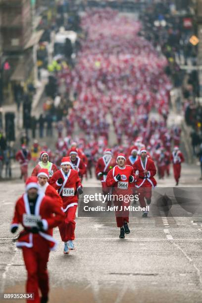 Over eight thousand members of the public take part in Glasgow's annual Santa dash make their way along St Vincent Street on December 10, 2017 in...