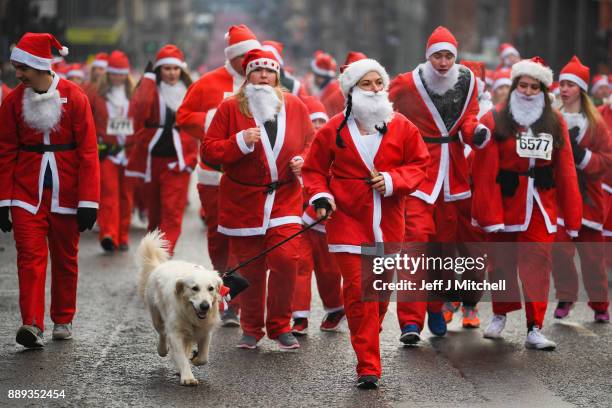 Over eight thousand members of the public take part in Glasgow's annual Santa dash make their way along St Vincent Street on December 10, 2017 in...