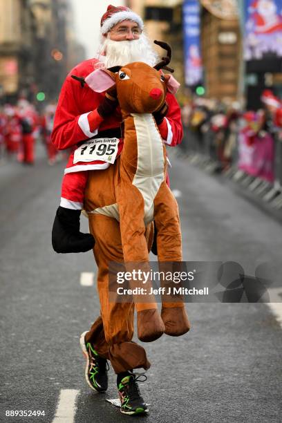 Over eight thousand members of the public take part in Glasgow's annual Santa dash make their way along St Vincent Street on December 10, 2017 in...