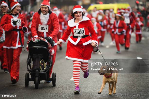 Over eight thousand members of the public take part in Glasgow's annual Santa dash make their way along St Vincent Street on December 10, 2017 in...