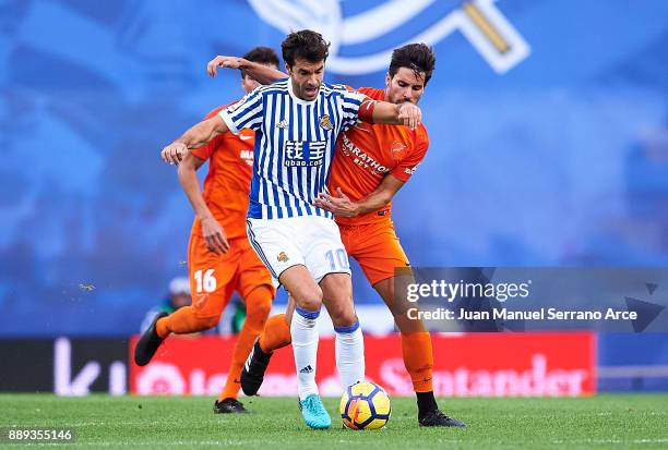 Xabier Prieto of Real Sociedad duels for the ball with Adrian Gonzalez of Malaga CF during the La Liga match between Real Sociedad de Futbol and Real...