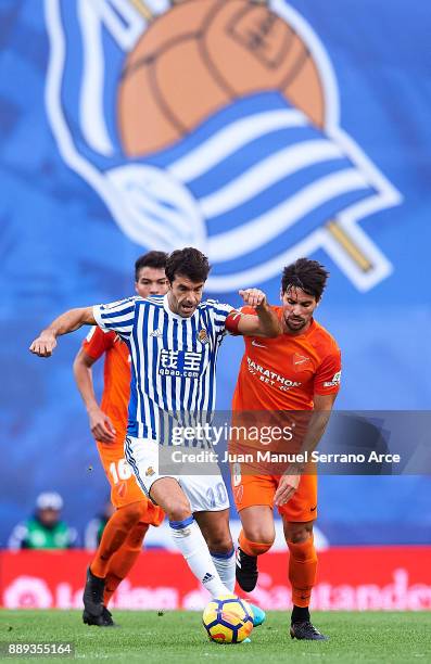 Xabier Prieto of Real Sociedad duels for the ball with Adrian Gonzalez of Malaga CF during the La Liga match between Real Sociedad de Futbol and Real...