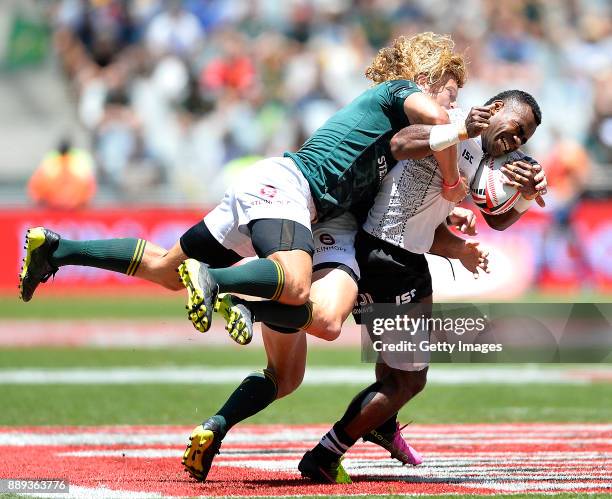 Jerry Tuwai of Fiji is tackled by Philip Snyman and Werner Kok of South Africa during day 2 of the 2017 HSBC Cape Town Sevens match between South...