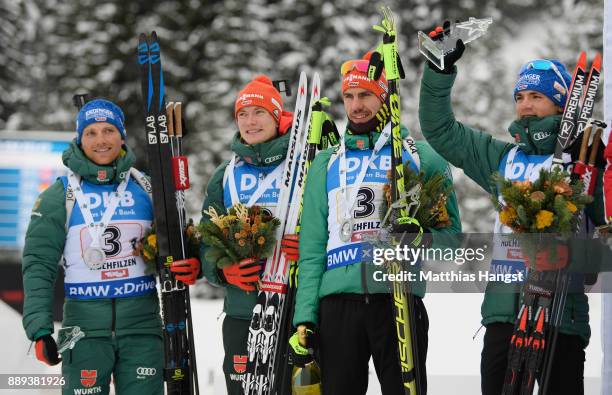 Erik Lesser of Germany, Benedikt Doll of Germany, Arnd Peiffer of Germany and Simon Schempp of Germany celebrate on the podium after the Men's...