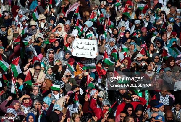 Pro-Palestinian protesters wave Palestinian flags and a poster reading in Arabic: "Our sacred places are calling us, for how long are we going to let...