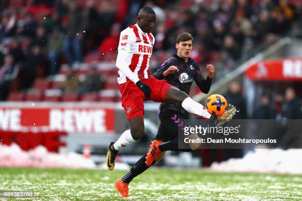 Sehrou Guirassy of FC Koeln is tackled by Pascal Stenzel of SC Freiburg during the Bundesliga match between 1. FC Koeln and Sport-Club Freiburg at...