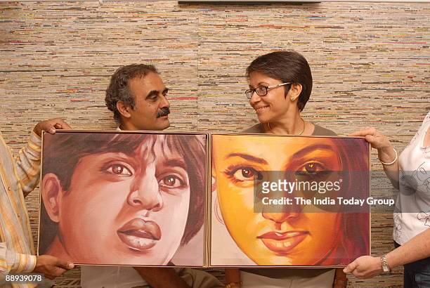 Anuradha and Manohar Patni, of Rickshaw Recycle, pose holding cinema poster created by cutting and framing a large handpainted film hoarding, in New...