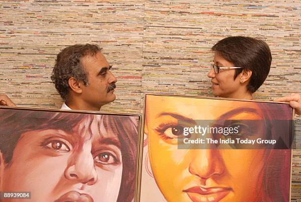 Anuradha and Manohar Patni, of Rickshaw Recycle, pose holding cinema poster created by cutting and framing a large handpainted film hoarding, in New...