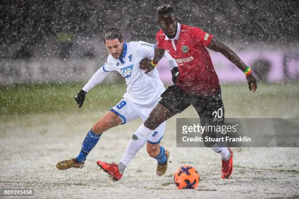 Mark Uth of 1899 Hoffenheim and Salif Sane of Hannover 96 battle for the ball during a heavy snow storm during the Bundesliga match between Hannover...