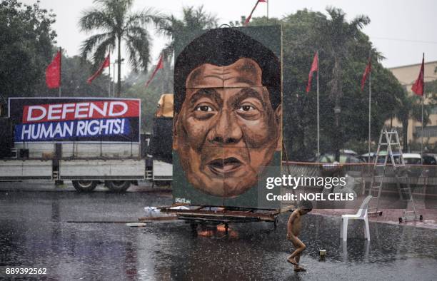 Child play as it rains during a protest in Manila on December 10 as activists commemorate the International Human Rights Day. Philippine President...